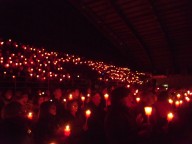Il palasport buio, illuminato solo dalle candele